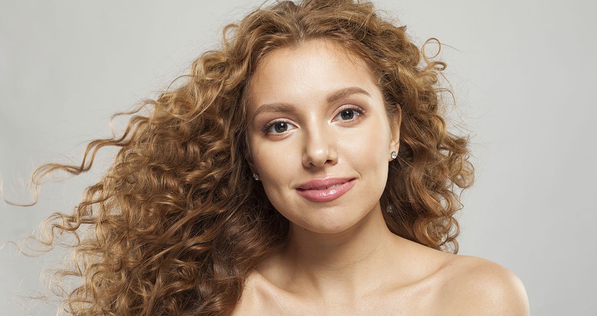 mulher branca de cabelo longos cacheadoscom tonalidade loiro acobreado
